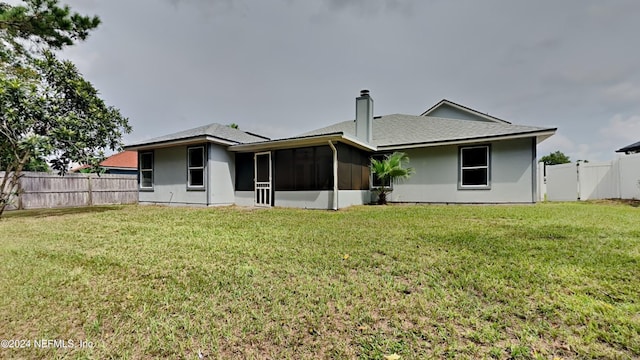 back of property with a lawn, a gate, a fenced backyard, a sunroom, and a chimney