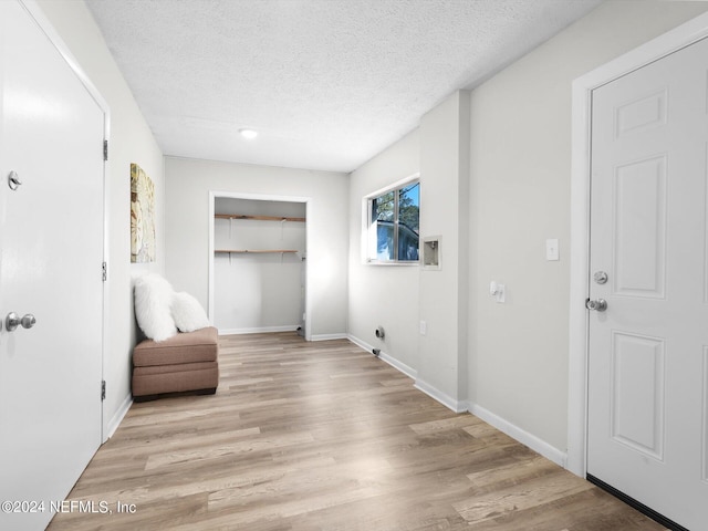 hallway with a textured ceiling and light hardwood / wood-style floors