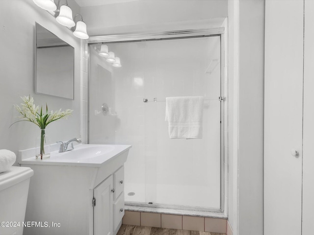 bathroom with toilet, vanity, hardwood / wood-style floors, and a shower with door