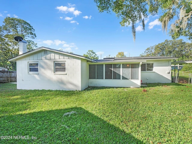 rear view of property featuring a sunroom and a lawn