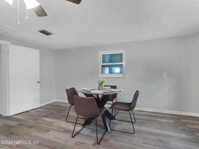 dining space featuring wood walls, hardwood / wood-style floors, and ceiling fan