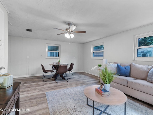 living room featuring a textured ceiling, light wood-type flooring, and ceiling fan