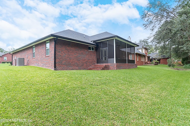 rear view of property featuring central AC, a lawn, and a sunroom