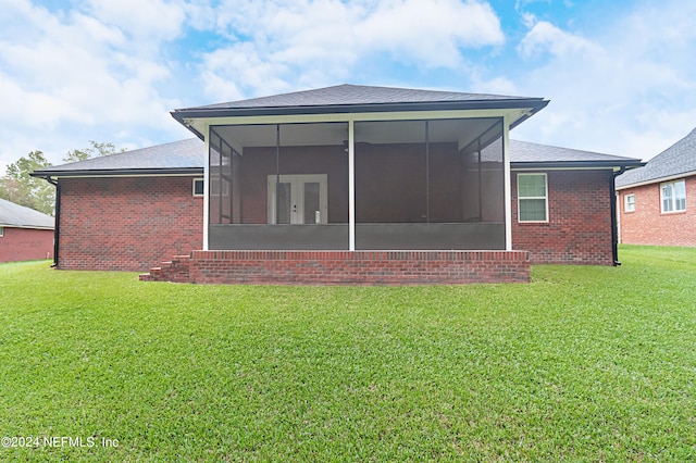 rear view of house featuring a lawn and a sunroom