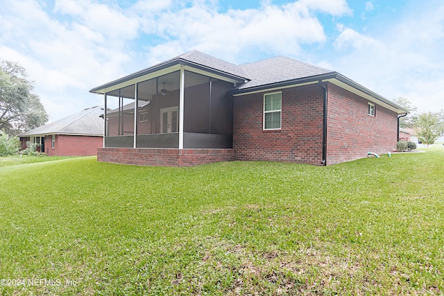 rear view of house with a lawn and a sunroom