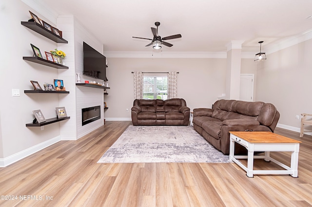 living room featuring light hardwood / wood-style floors, ornamental molding, a fireplace, and ceiling fan