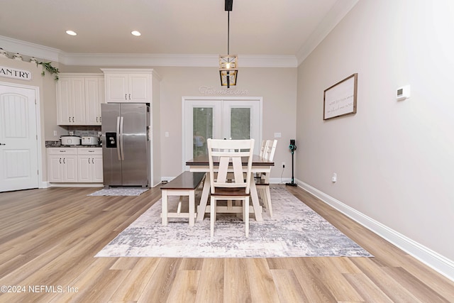 dining room with crown molding, light wood-type flooring, and french doors