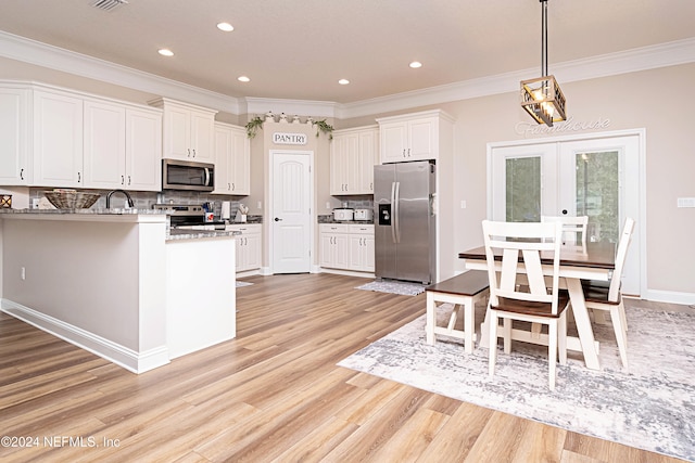 kitchen with light hardwood / wood-style floors, crown molding, white cabinets, and stainless steel appliances