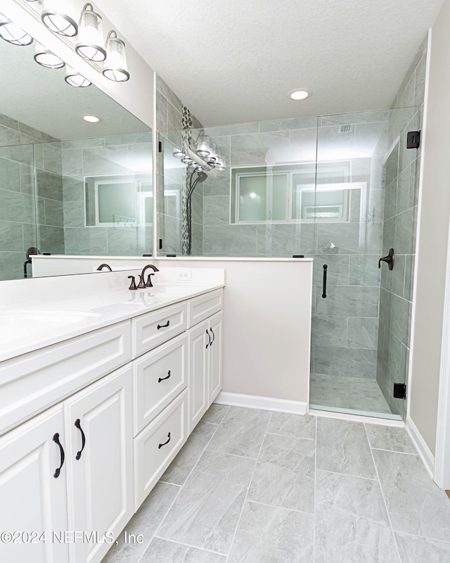 bathroom featuring vanity, a textured ceiling, and a shower with door