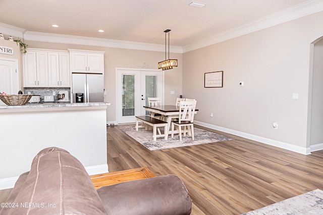 kitchen featuring white cabinetry, decorative light fixtures, crown molding, dark hardwood / wood-style floors, and stainless steel refrigerator with ice dispenser