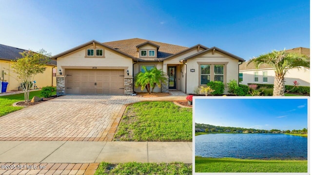 view of front facade with stone siding, an attached garage, a water view, decorative driveway, and stucco siding