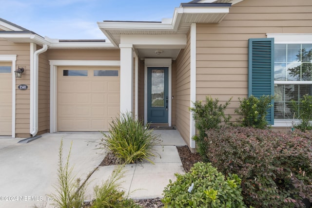 property entrance featuring an attached garage and driveway