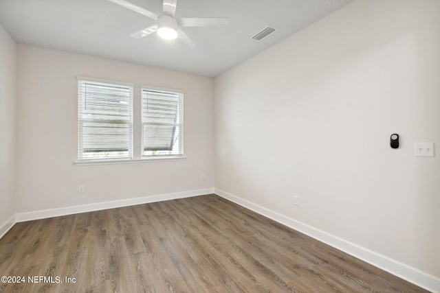 spare room with baseboards, wood finished floors, visible vents, and a ceiling fan