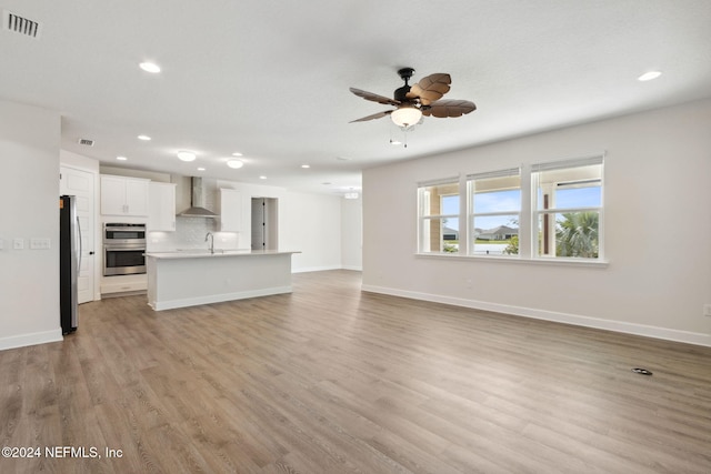 unfurnished living room featuring a sink, light wood-type flooring, ceiling fan, visible vents, and recessed lighting