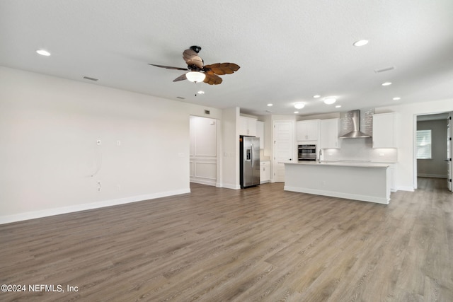 unfurnished living room featuring ceiling fan, a textured ceiling, light hardwood / wood-style flooring, and sink