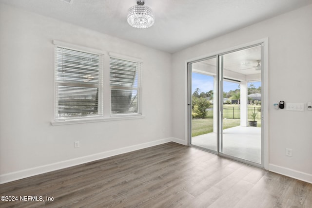 spare room featuring baseboards, a chandelier, and wood finished floors