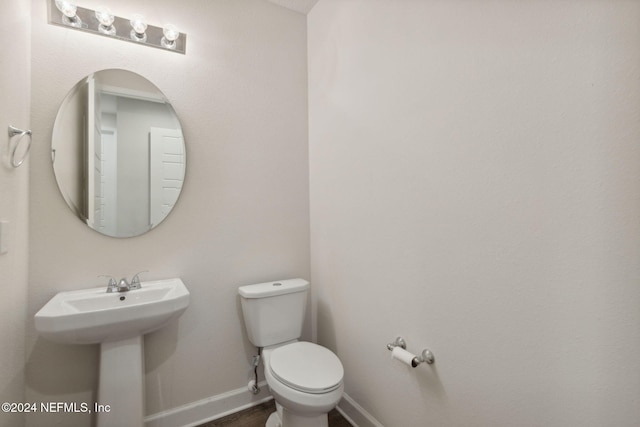 half bathroom featuring baseboards, a sink, and toilet