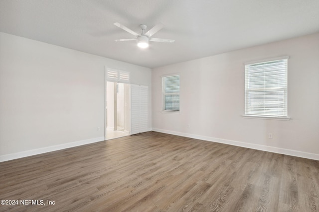 unfurnished room with baseboards, wood finished floors, ceiling fan, and a healthy amount of sunlight