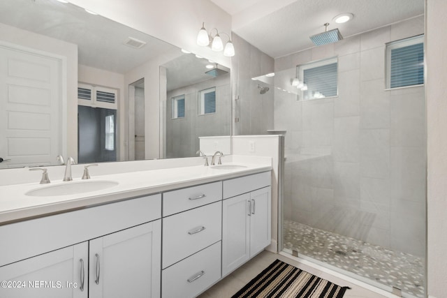 full bath featuring walk in shower, visible vents, a sink, and double vanity