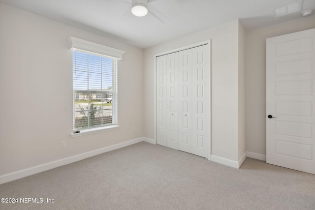 unfurnished bedroom featuring light carpet, a closet, and ceiling fan