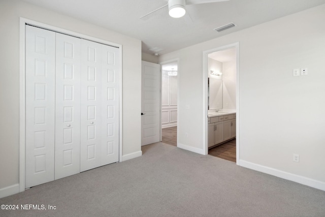 unfurnished bedroom with ensuite bathroom, a closet, carpet, baseboards, and visible vents