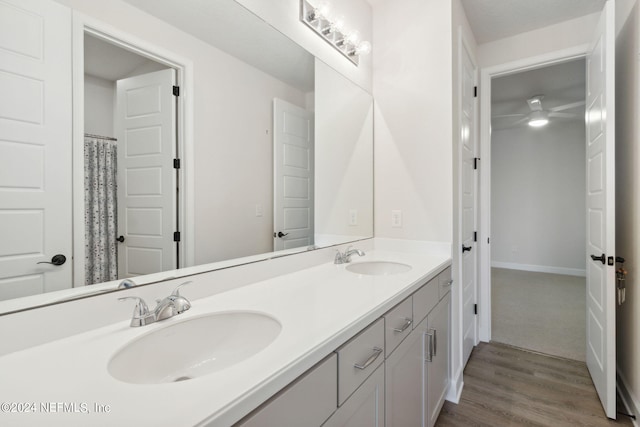 full bathroom featuring double vanity, wood finished floors, baseboards, and a sink