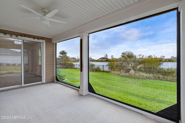unfurnished sunroom with ceiling fan and a water view