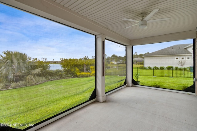 unfurnished sunroom with a ceiling fan and a water view