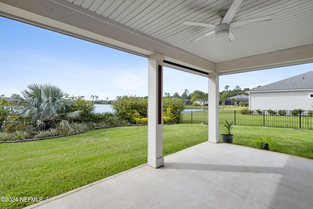 view of patio / terrace with a water view, ceiling fan, and fence