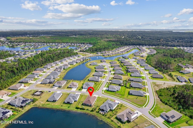 drone / aerial view featuring a wooded view, a residential view, and a water view