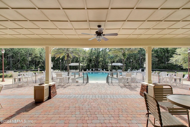 view of patio featuring fence, ceiling fan, and a community pool