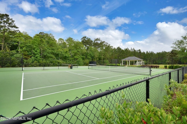 view of sport court with a view of trees, community basketball court, and fence