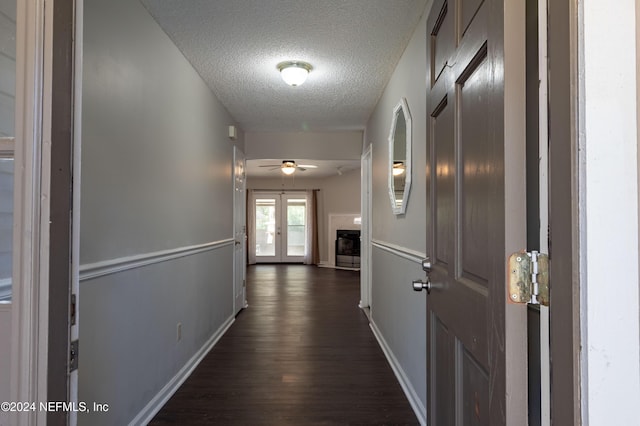 hallway featuring french doors, dark wood-type flooring, and a textured ceiling