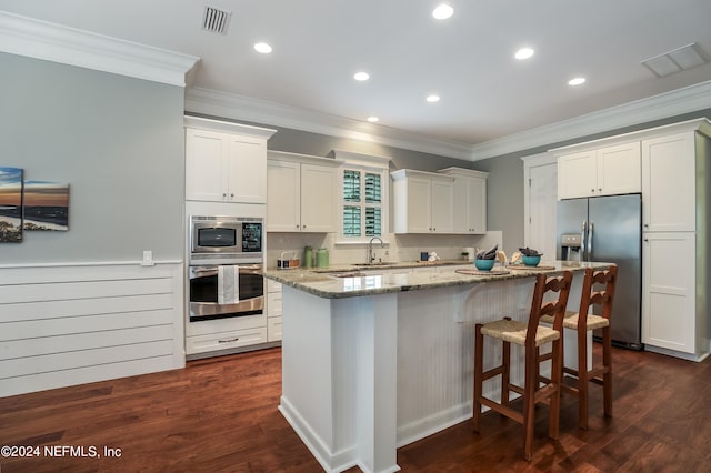 kitchen featuring white cabinets, appliances with stainless steel finishes, a center island, light stone countertops, and dark hardwood / wood-style flooring