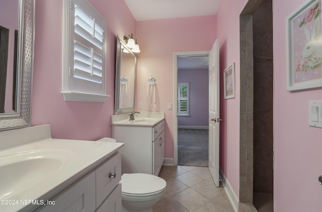 bathroom with tile patterned flooring, a wealth of natural light, vanity, and toilet