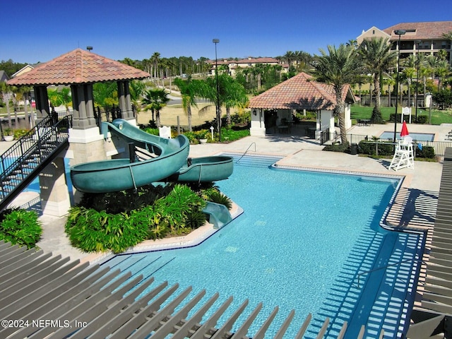 view of swimming pool with a gazebo, a water slide, and a patio area