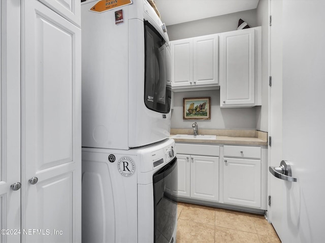 laundry area featuring sink, stacked washing maching and dryer, light tile patterned floors, and cabinets