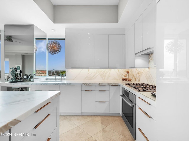 kitchen featuring light stone counters, white cabinets, appliances with stainless steel finishes, and sink