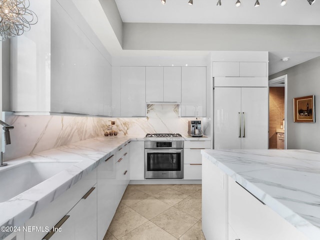 kitchen with light stone counters, sink, white cabinetry, appliances with stainless steel finishes, and decorative backsplash