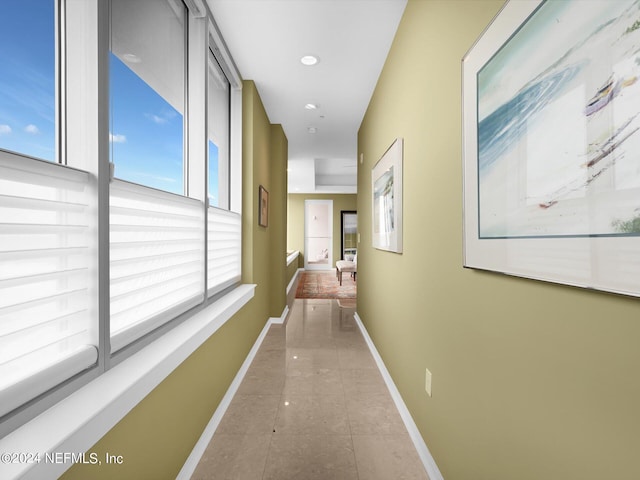 hallway featuring light tile patterned floors and a healthy amount of sunlight