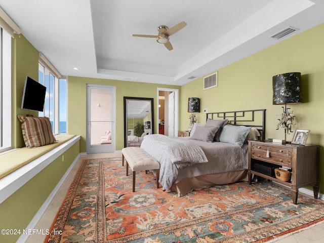 bedroom with a raised ceiling, tile patterned flooring, and ceiling fan