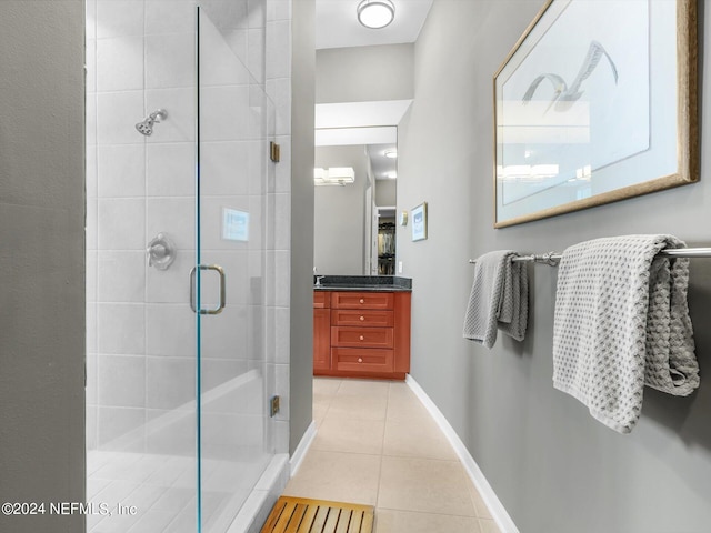 bathroom featuring tile patterned flooring, a shower with door, and vanity