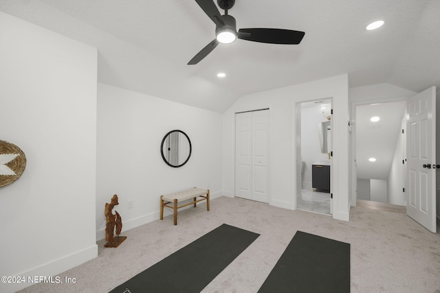 exercise area featuring ceiling fan, lofted ceiling, and light colored carpet