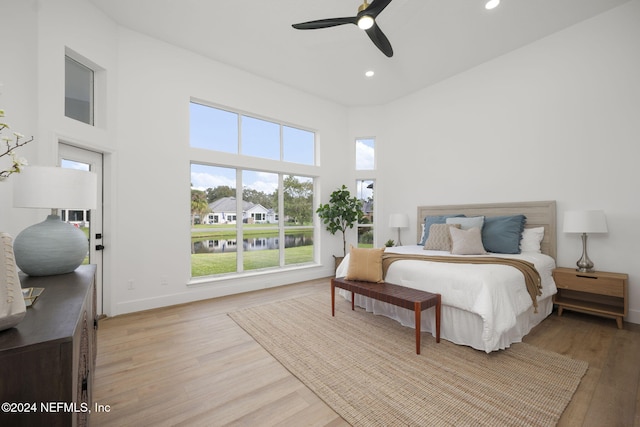 bedroom featuring a towering ceiling, light wood-type flooring, and ceiling fan