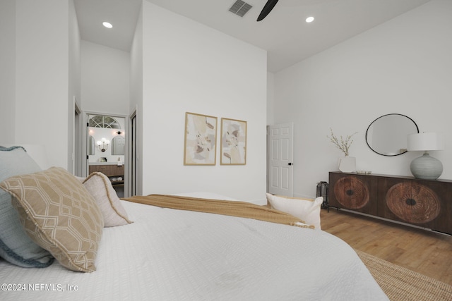 bedroom with connected bathroom, high vaulted ceiling, hardwood / wood-style flooring, and ceiling fan