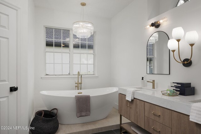 bathroom with vanity, a notable chandelier, and a washtub