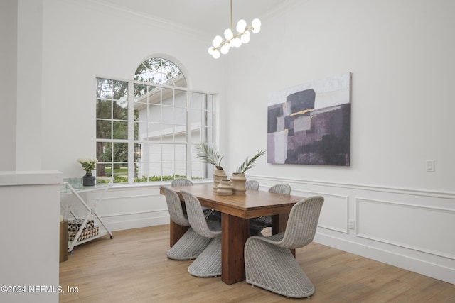 dining space with ornamental molding, light hardwood / wood-style flooring, a notable chandelier, and a healthy amount of sunlight