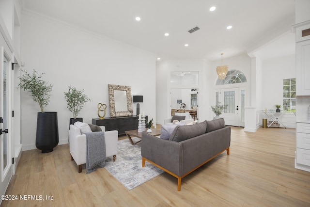 living room featuring a towering ceiling, ornamental molding, and light wood-type flooring