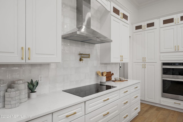 kitchen featuring black electric stovetop, white cabinetry, and wall chimney range hood