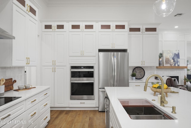 kitchen with backsplash, white cabinetry, stainless steel appliances, light hardwood / wood-style floors, and sink